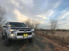 Load image into Gallery viewer, Baja Designs S2 Sport LED lights mounted on a Toyota 4Runner parked on a scenic dirt road at sunset.