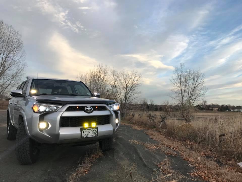 Baja Designs S2 Sport LED lights mounted on a Toyota SUV, illuminating a rural road with a scenic backdrop.