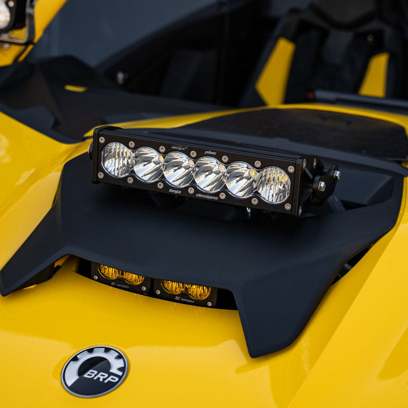 Baja Designs Can-Am Maverick R Clear 10in OnX6+ Shock Tower Kit mounted on a yellow vehicle, enhancing off-road visibility.