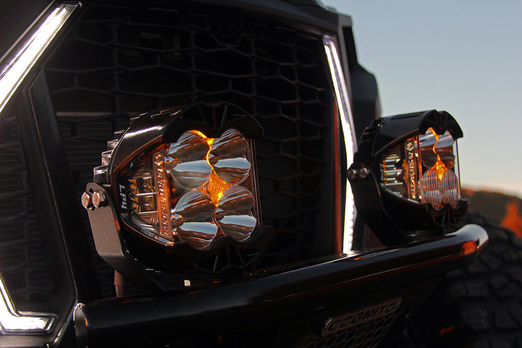 Baja Designs LP4 Pro LED spot lights mounted on a vehicle's front grille, showcasing bright illumination for offroad use.
