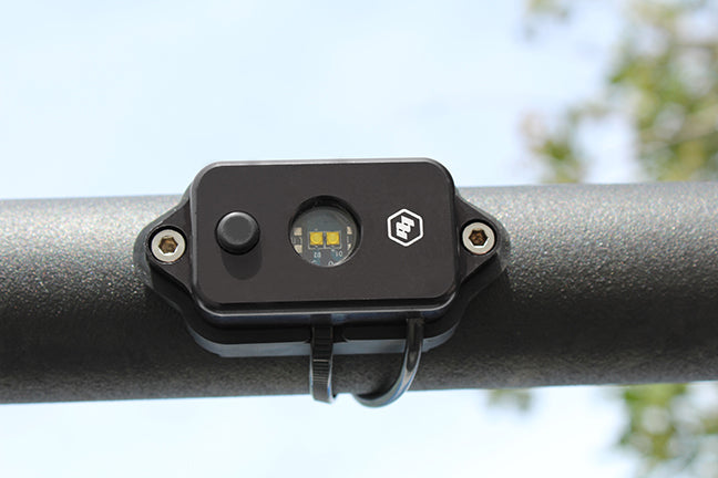 Baja Designs LED dome light with switch in green, mounted on a bar, designed for offroad vehicles and outdoor use.